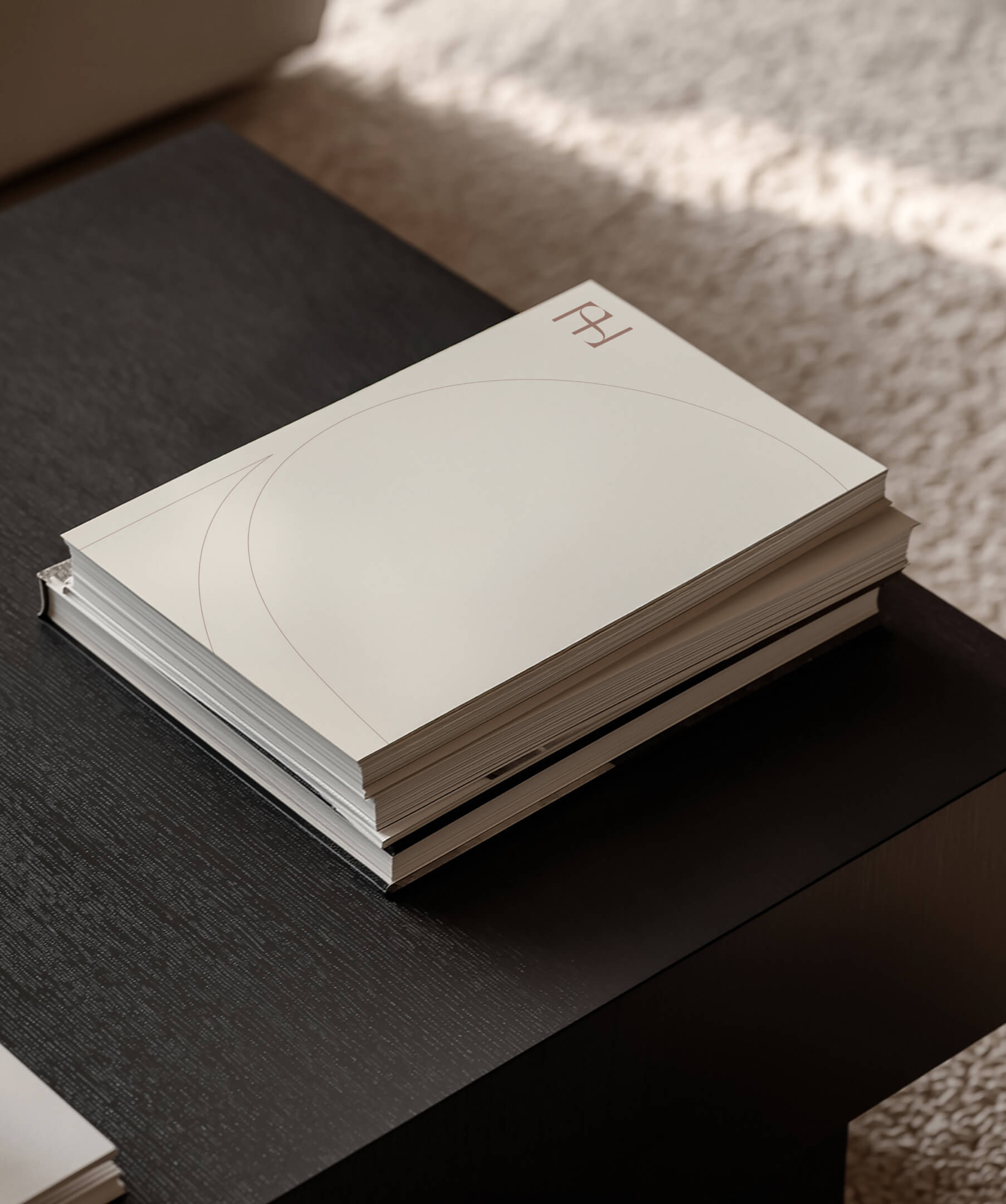 Stack of SHH branded notebooks on dark wood table.