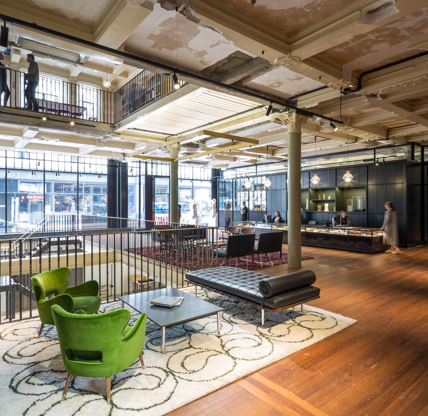Lounge seating area with green armchairs and mezzanine inside The Department Store Brixton