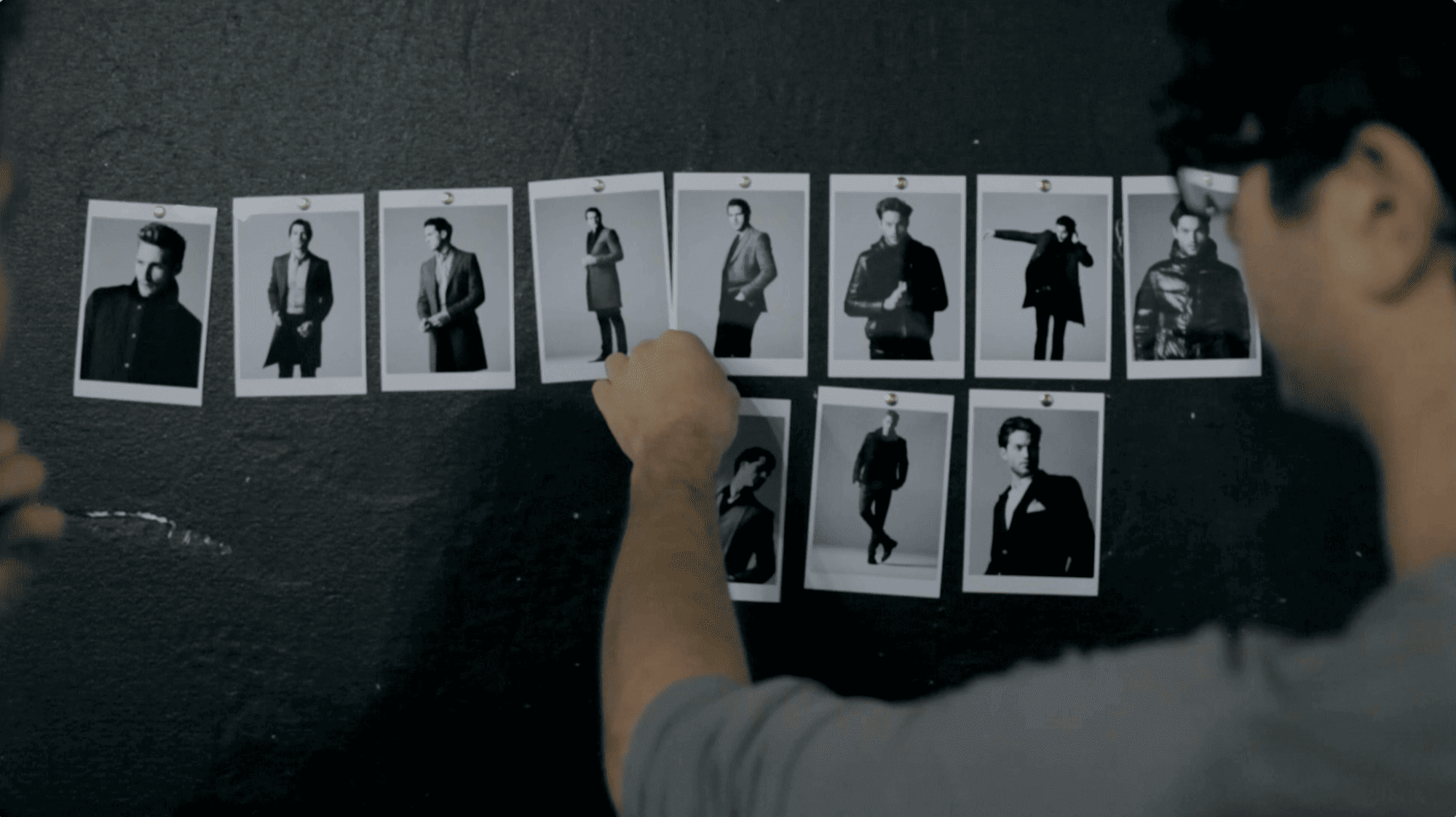 Close-up of a designer reviewing printed black-and-white photographs at a desk. Video of backstage photoshoot