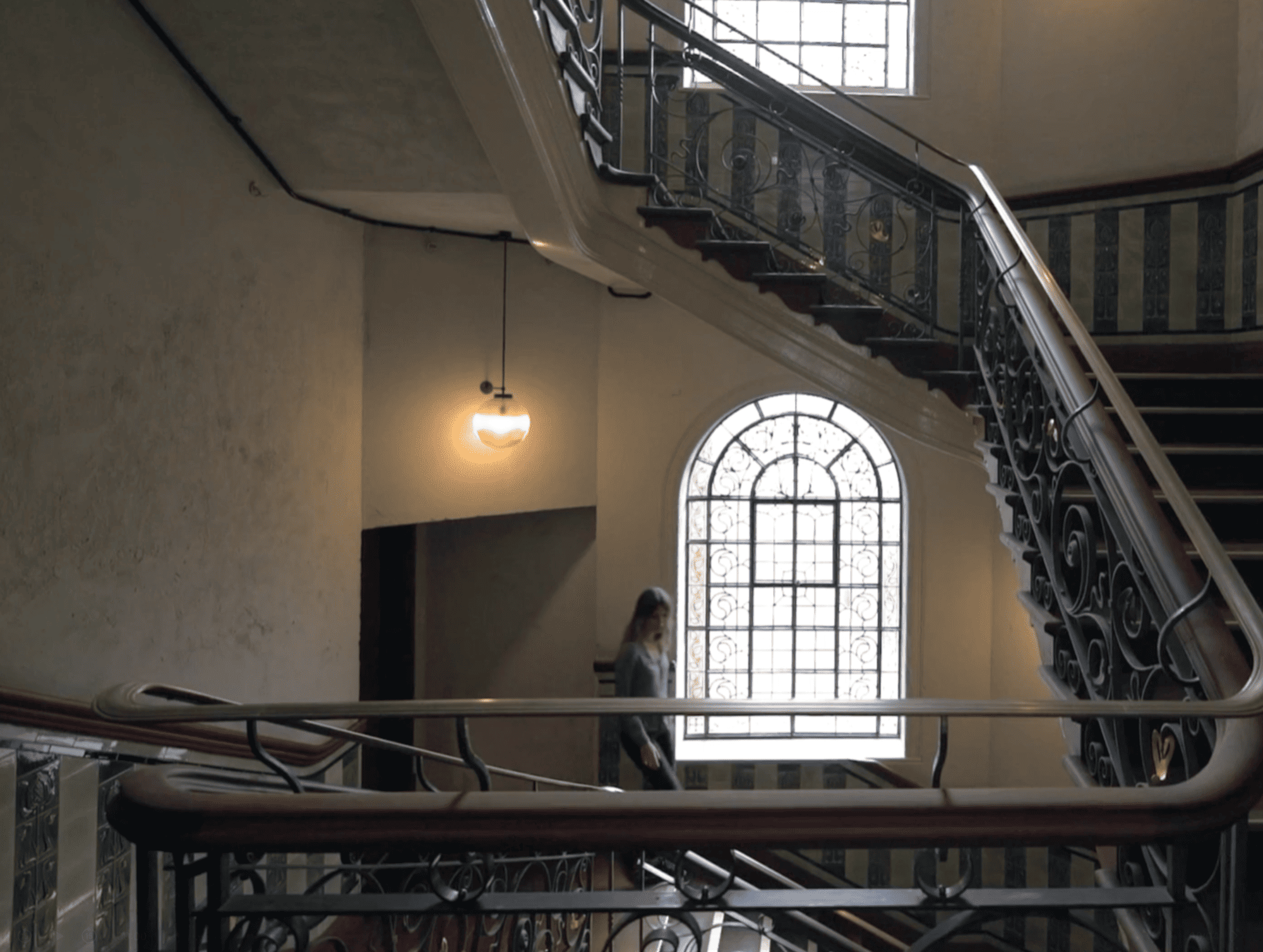 Historic iron staircase and large arched window inside The Department Store Brixton.